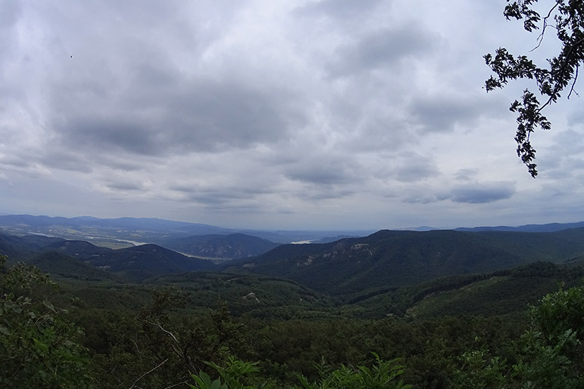 Magyarországi túra: Felhős ég, napsütötte zöld dombok és távoli hegyek, ideális kiránduláshoz vagy túrázáshoz a természetben. Tekeregj.hu
