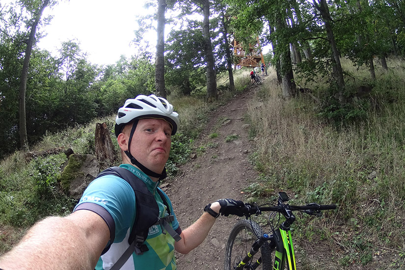 Magyarországi túra: Férfi selfie-t készít mountain bike-ján egy kirándulás során, lenyűgöző panorámát mutatva a természetben. Tekeregj.hu