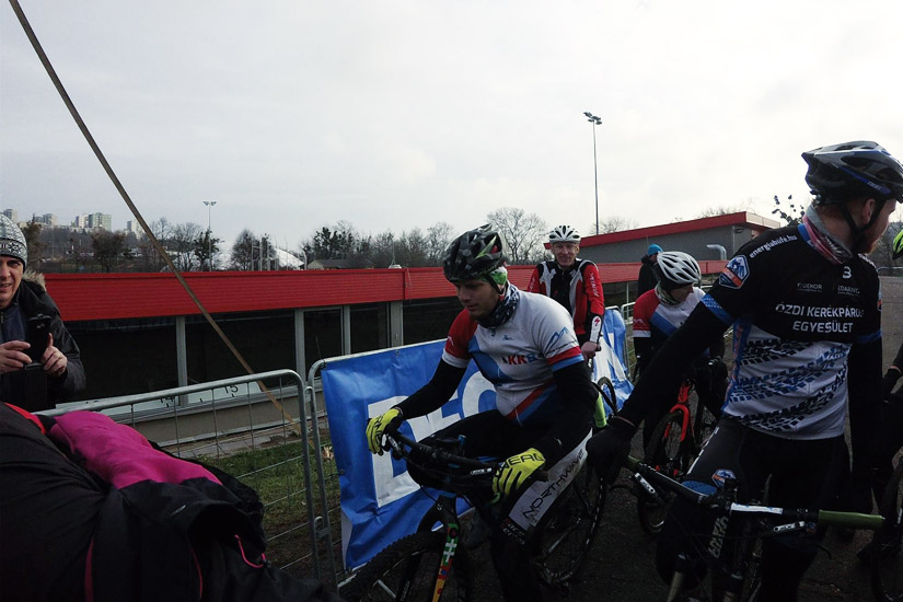 Magyarországi túra: Kerékpárosok pihennek egy hegyi túra során kinti rendezvényen, fémkorlát mellett, biciklivel. Tekeregj.hu