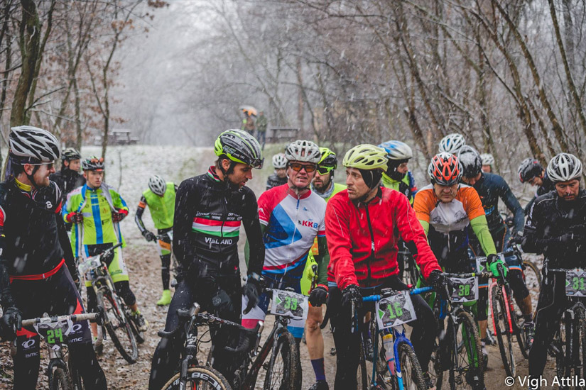 Magyarországi túra: Kerékpárosok sisakban, színes ruhában gyülekeznek havas erdei úton, téli túrára készülve. Tekeregj.hu