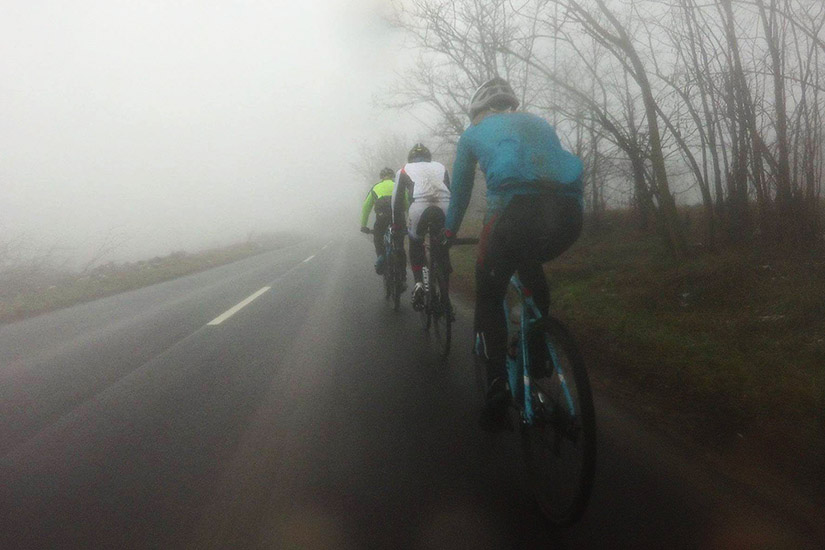 Magyarországi túra: Négy kerékpáros teker ködös, elhagyatott úton kopár fák között; kalandos hegyi túrázás természetben. Tekeregj.hu