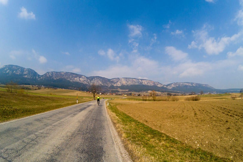 Magyarországi túra: Kerékpáros vidéki úton, mezők és távoli hegyek között, kék ég alatt. Élménydús kirándulás természeti panorámával. Tekeregj.hu