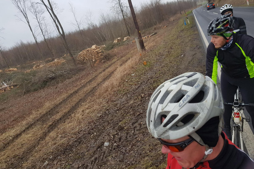 Magyarországi túra: Két sisakos kerékpáros halad sáros úton erdőirtott területen, borús időben, kalandos természetjárás közben. Tekeregj.hu