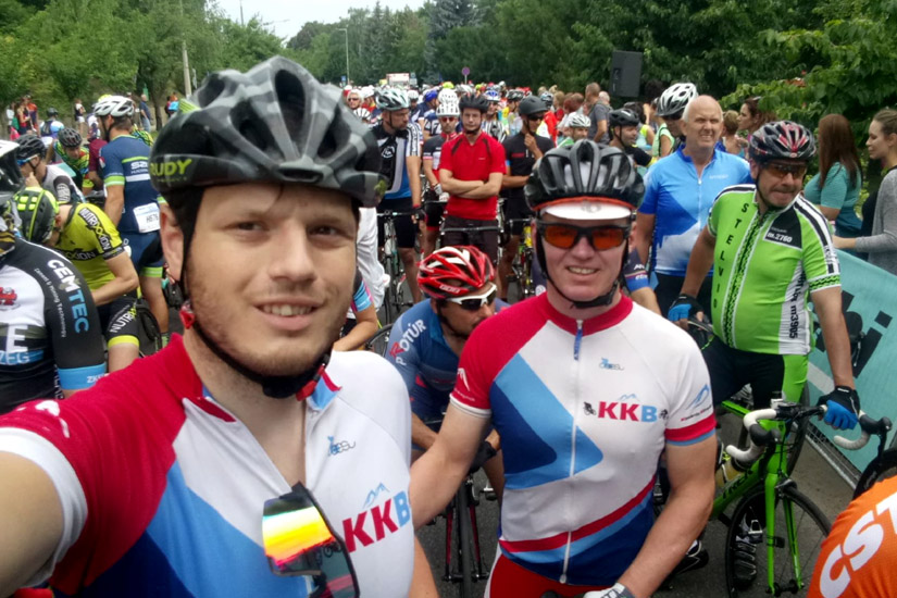 Magyarországi túra: Két hozás az élvonalban, mezben szelfizik egy budapesti városi túra rajtjánál, hátul színes sisakos csoport. Tekeregj.hu