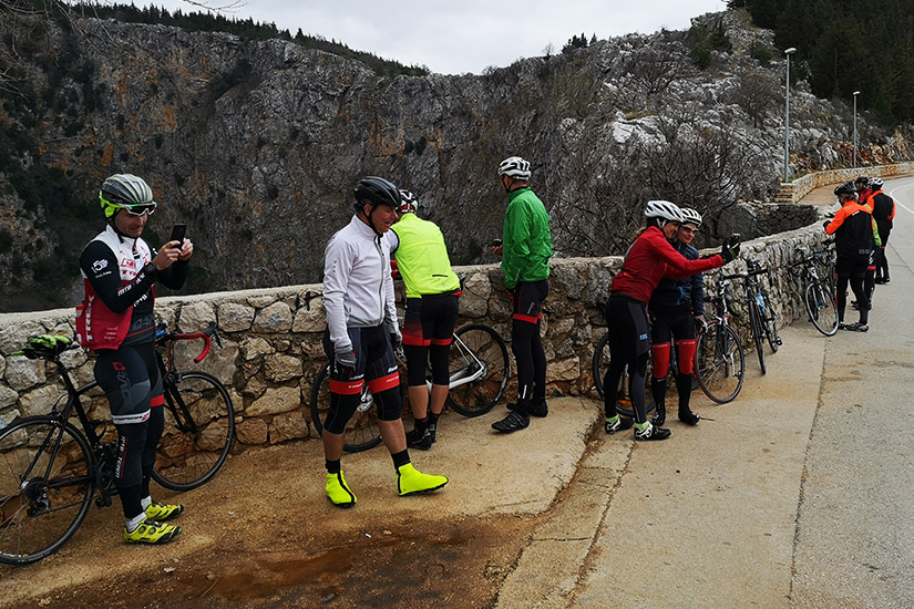 Magyarországi túra: Színes nyugás kerékpárosok pihennek egy hegyi úton, hátterükben sziklák és fák; természetjárás a panorámás tájon. Tekeregj.hu