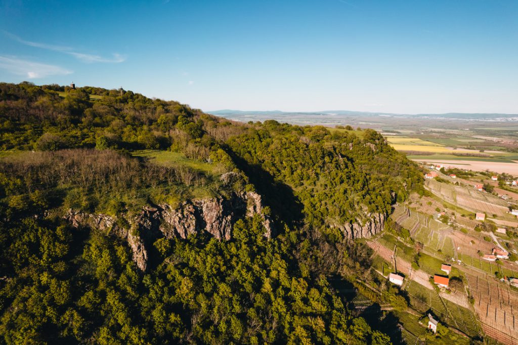 Magyarországi túra: Légi felvétel zöld, sziklás hegyekről természetjáráshoz, völgyben házakkal, tiszta ég alatt, csodás panorámával. Tekeregj.hu