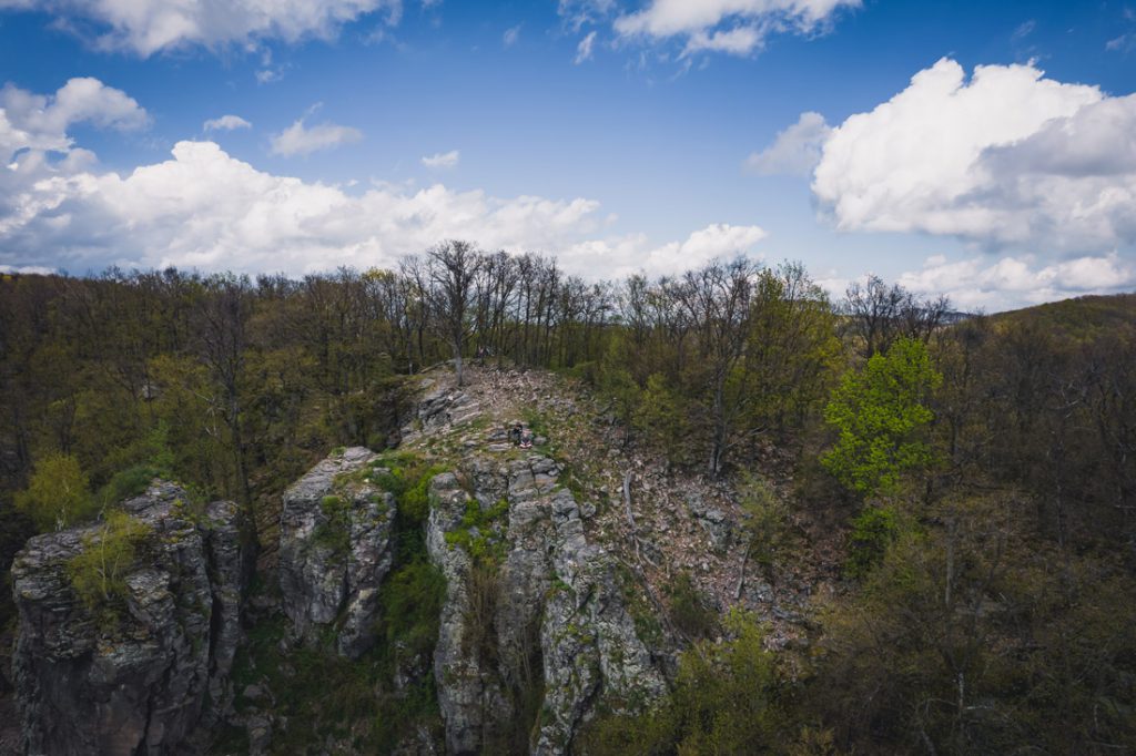 Magyarországi túra: Sziklás szirt lombos fák közt, kék ég alatt; tavaszi hegyi túra útvonal, lenyűgöző panorámával. Tekeregj.hu