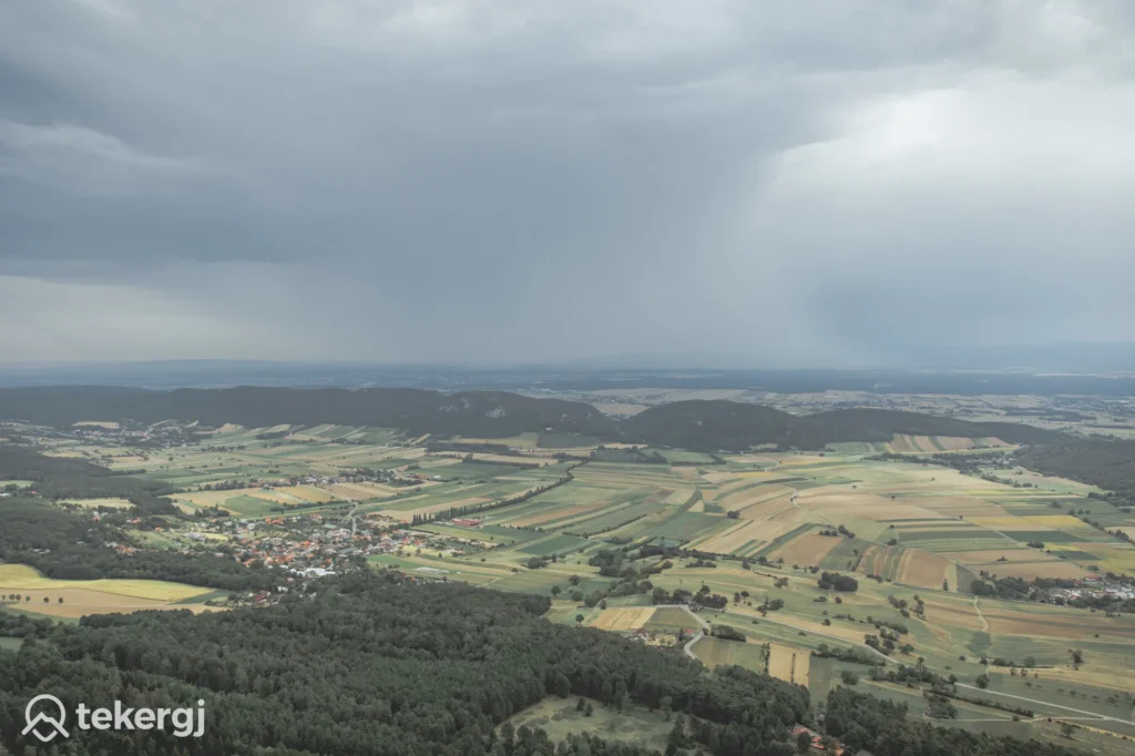 Magyarországi túra: Légi fotó mozaikos mezőkről, kis faluról és erdőről felhős ég alatt, ideális gyalogtúrához. tekerj vízjel bal lent. Tekeregj.hu