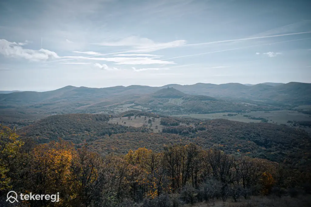 Magyarországi túra: Őszi dombvidéki panoráma erdőkkel, hegyi túrához ideális táj, felhős égbolt, tekeregi logó bal alsó sarokban. Tekeregj.hu
