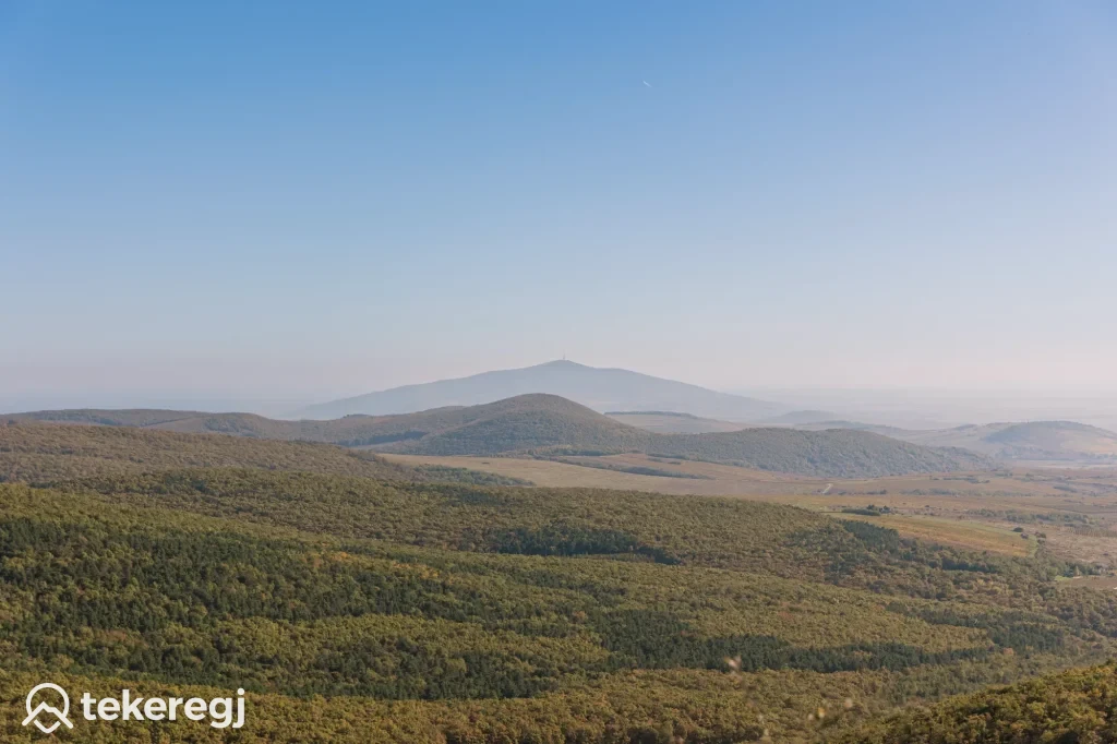 Magyarországi túra: Panorámakép zöld dombokról, fákkal, háttérben hegycsúccsal, tiszta ég alatt. Séta vagy kerékpártúra ajánlott. "Tekeregj" felirat. Tekeregj.hu