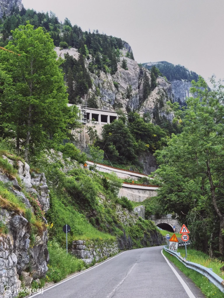 Magyarországi túra: Kanyargós út a Monte Zoncolanon, alagutak, figyelmeztető táblák és zöldellő hegyoldal a túrázók és kerékpárosok számára. Tekeregj.hu